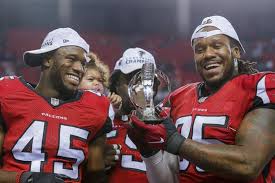  Falcon players holding the NFC Championship Trophy
